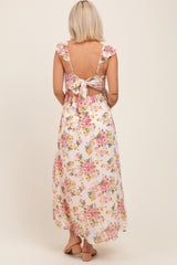 woman wearing a floral maxi maternity dress with ruffled straps and a back tie detail, showing her baby bump