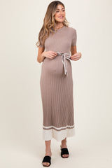 woman wearing a beige ribbed maternity dress with a belted waist and contrasting hem, showing her baby bump