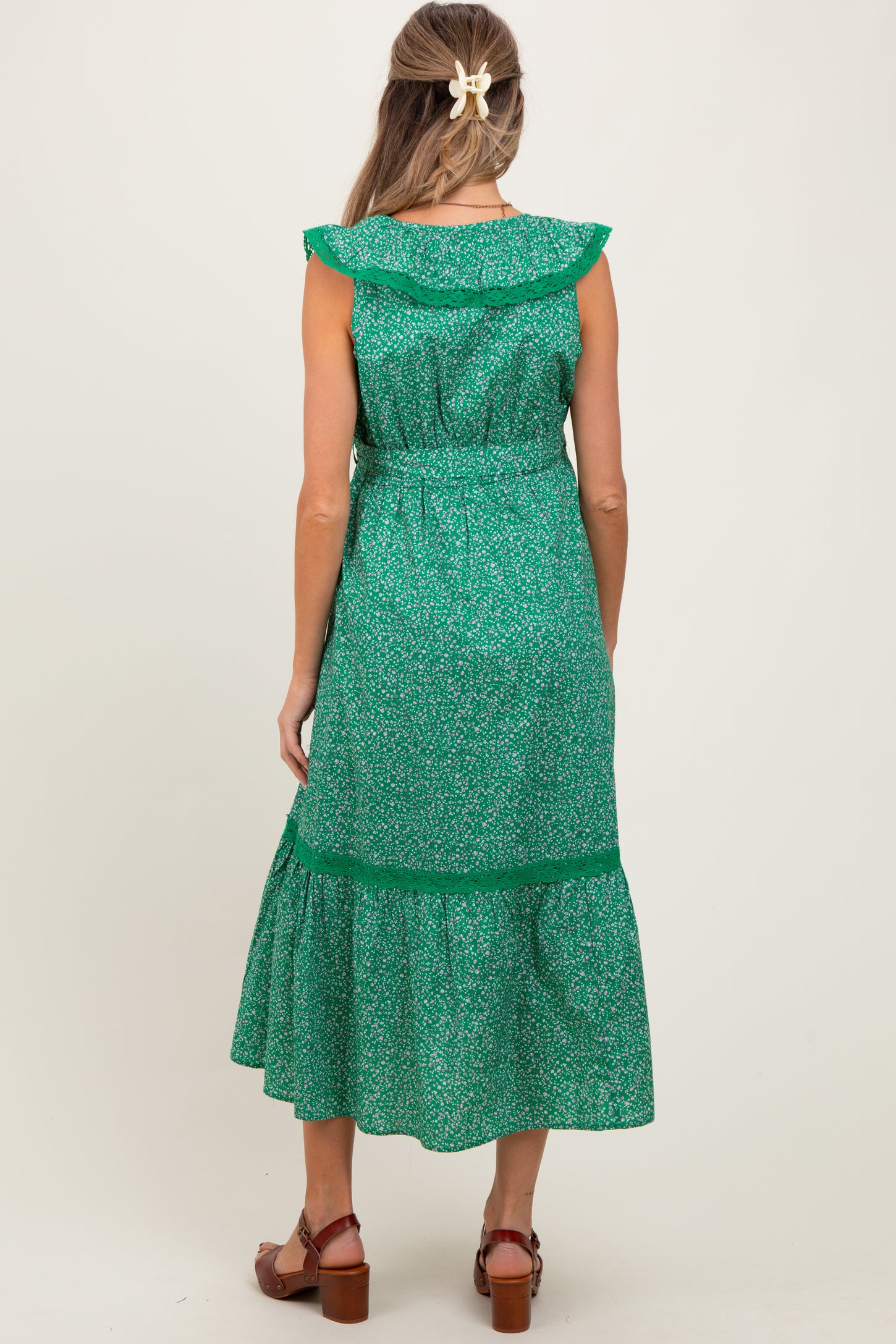 woman wearing a green floral maternity dress with ruffle details and a tiered skirt, showing her baby bump