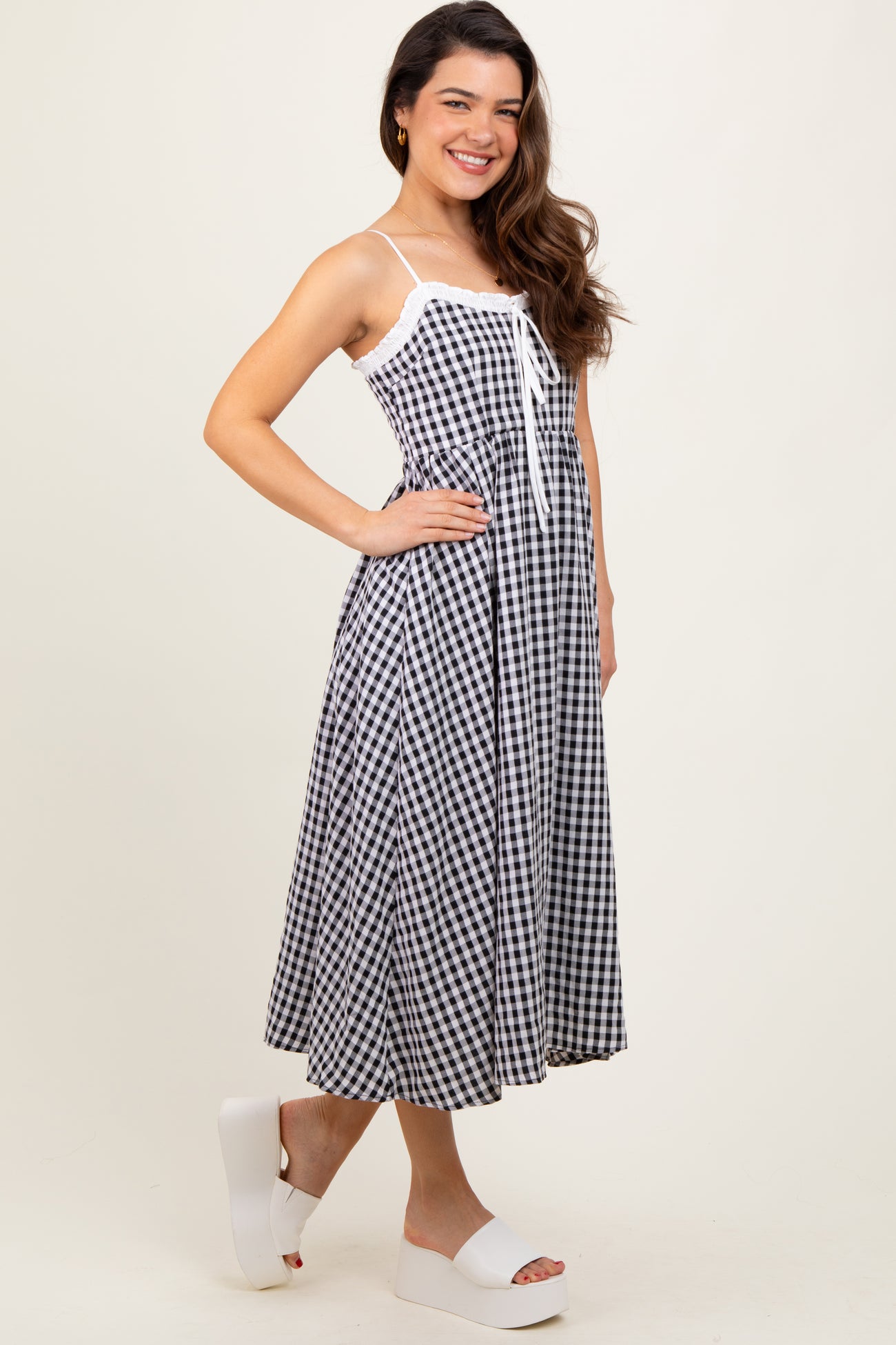 woman wearing a black and white gingham midi dress with spaghetti straps and a tie detail at the front