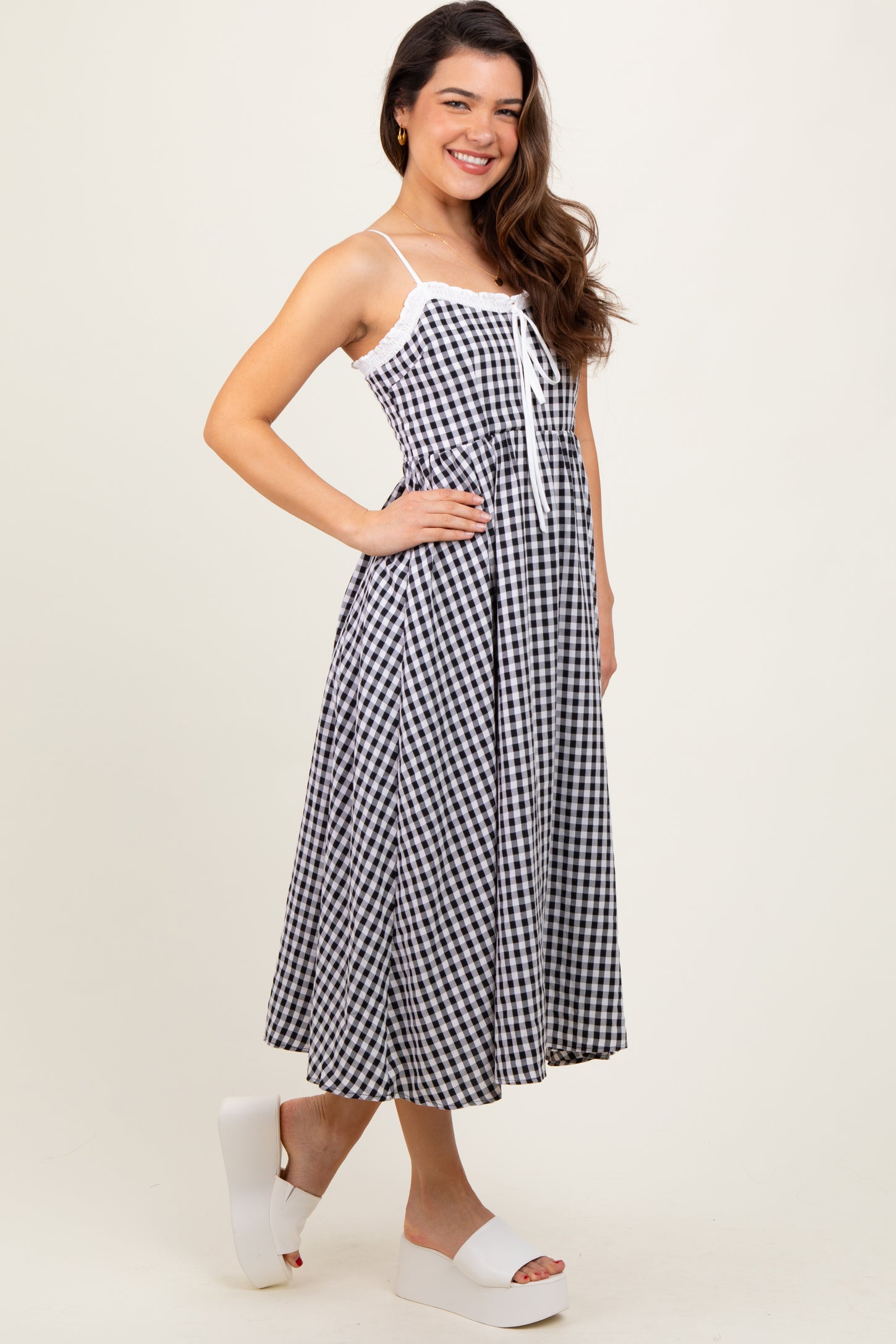 woman wearing a black and white gingham midi dress with spaghetti straps and a tie detail at the front