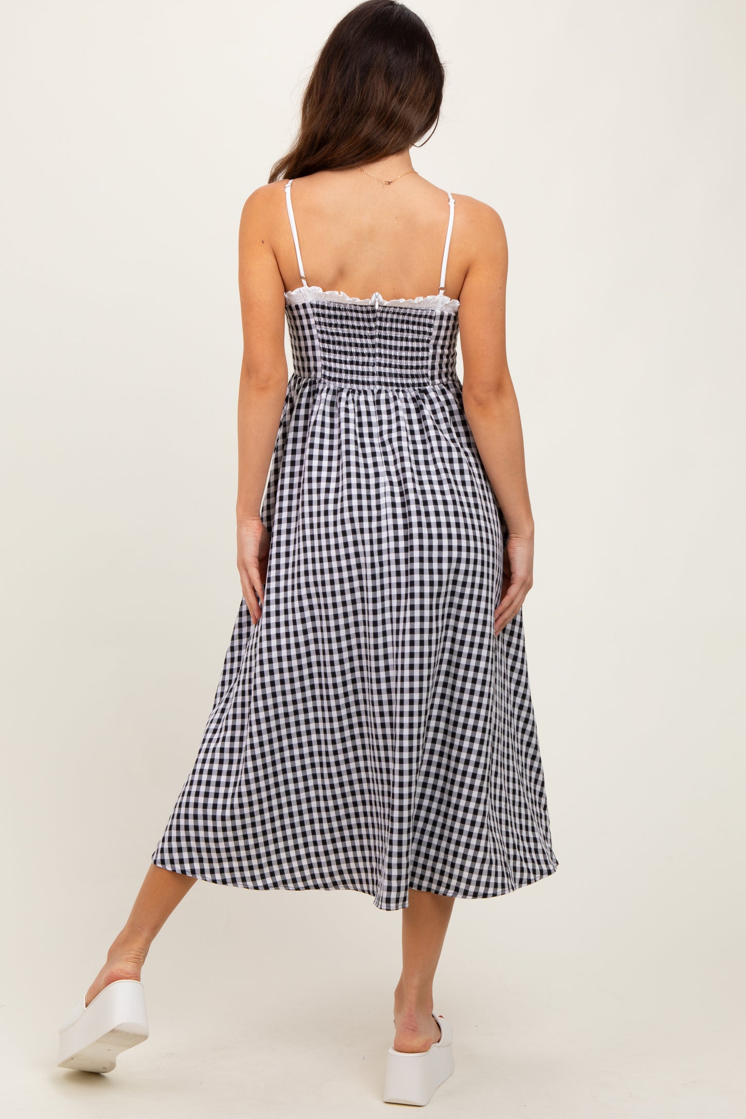woman wearing a black and white gingham midi dress with a fitted bodice and flowy skirt, viewed from the back