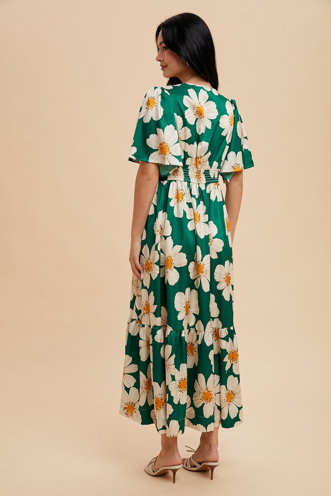 woman wearing a green floral maxi dress with short flutter sleeves, showcasing a tiered skirt and smocked back design