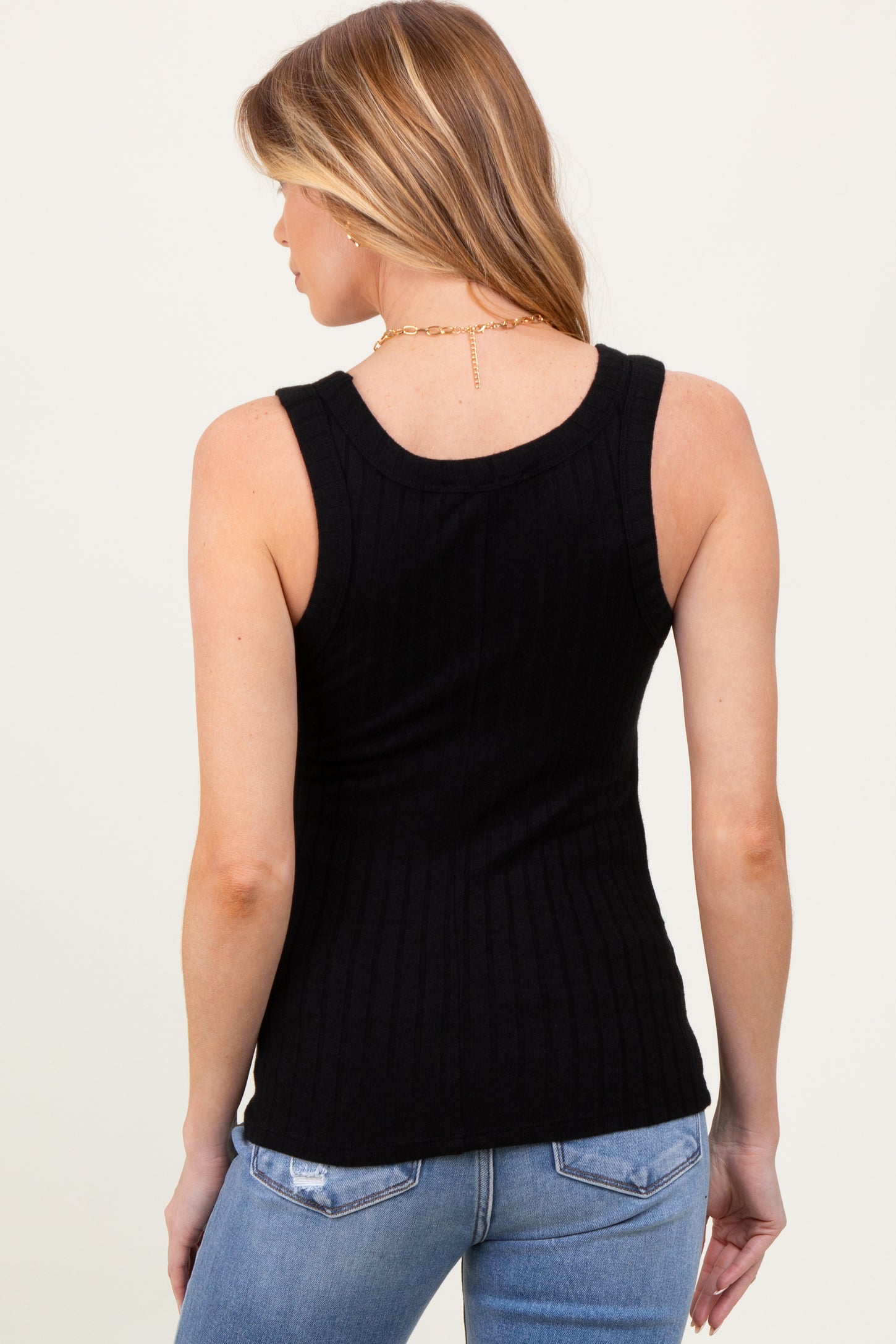 woman wearing a black ribbed maternity tank top, shown from the back with blue jeans