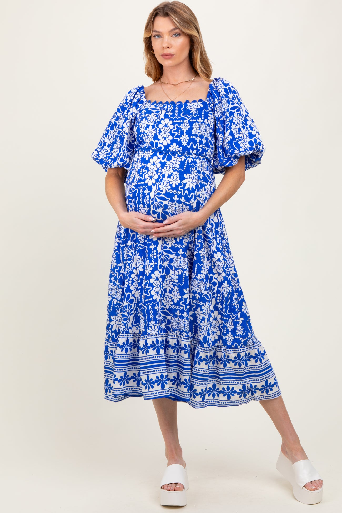 woman wearing a blue floral maternity dress with puff sleeves and a baby bump visible