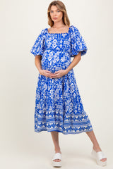 woman wearing a blue floral maternity dress with puff sleeves and a baby bump visible