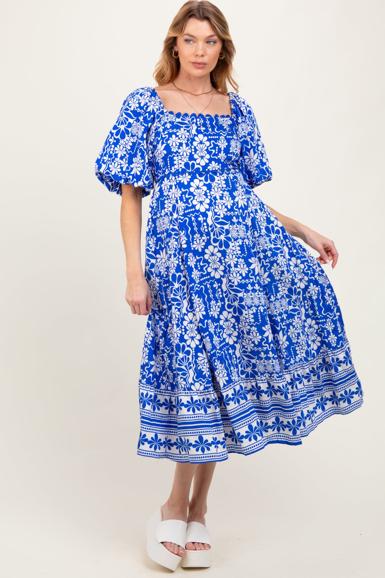 woman wearing a blue floral patterned maternity dress with puff sleeves and a square neckline