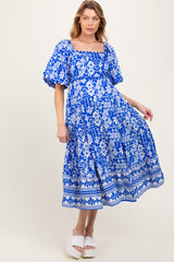 woman wearing a blue floral patterned maternity dress with puff sleeves and a square neckline