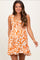 woman wearing an orange and white floral print maternity dress with a smocked bodice and ruffled straps