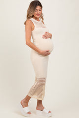 woman wearing a cream crochet knit maternity dress and holding her baby bump