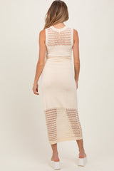 woman wearing a cream knit maternity dress with a fitted silhouette and open knit detailing, showing her baby bump