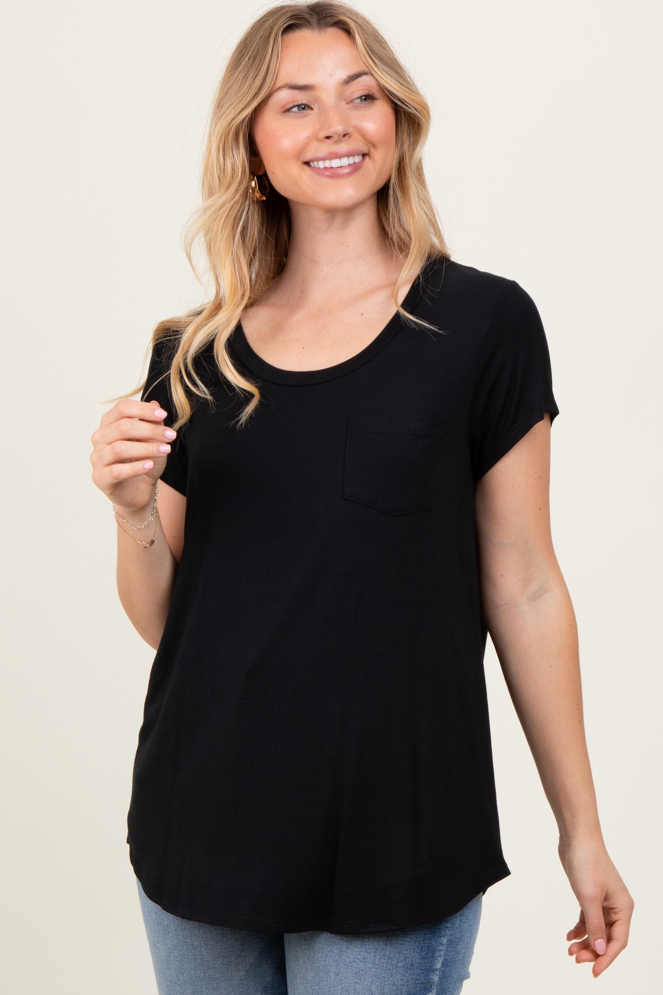 woman wearing a black short sleeve t-shirt with a pocket and a rounded hem, smiling and posing
