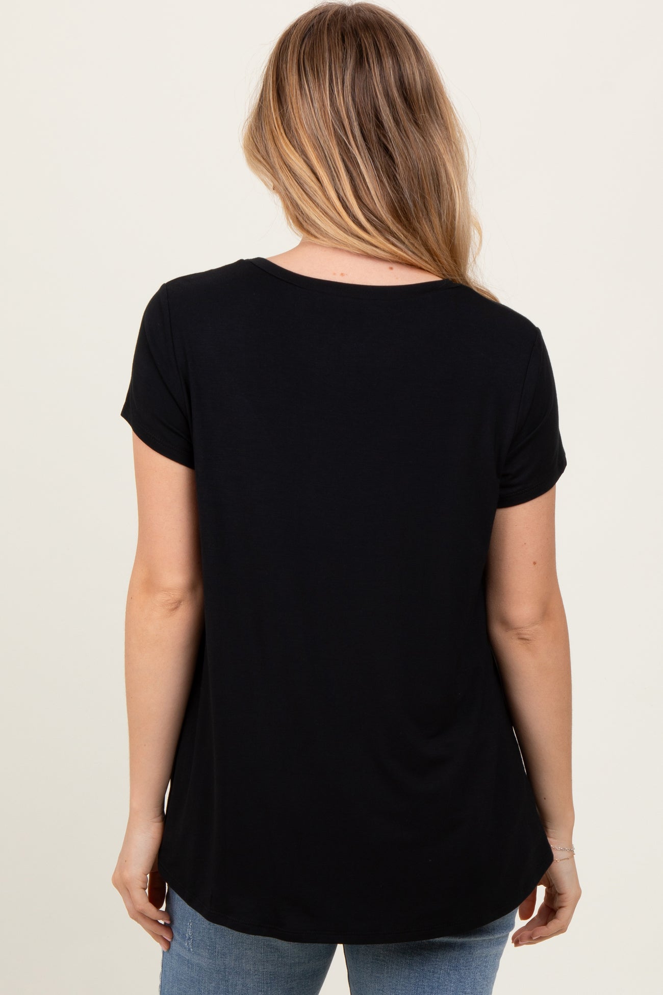 woman wearing a black short sleeve top, viewed from the back, paired with light blue jeans