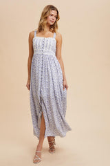 woman wearing a white floral maxi dress with thin straps and a gathered bodice