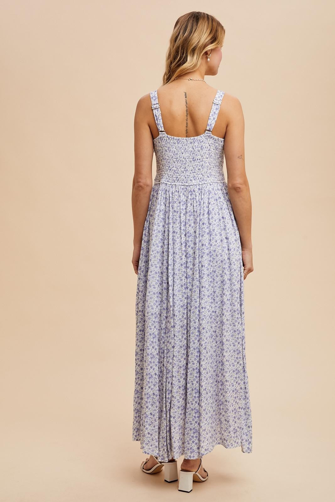 woman wearing a purple floral maxi dress with a smocked bodice and wide straps, shown from the back