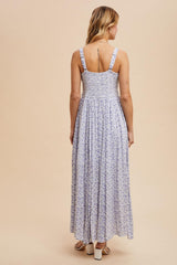 woman wearing a purple floral maxi dress with a smocked bodice and wide straps, shown from the back