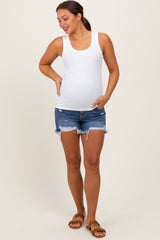 woman wearing a white ribbed maternity tank top and distressed denim shorts, displaying her baby bump