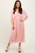 woman wearing a light pink pleated midi dress with a flowy cape sleeve and a cinched waist