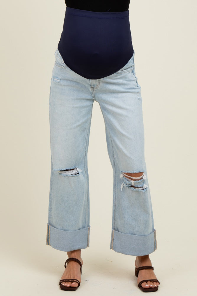 woman wearing a navy blue maternity belly band with distressed light wash mom jeans and brown sandals