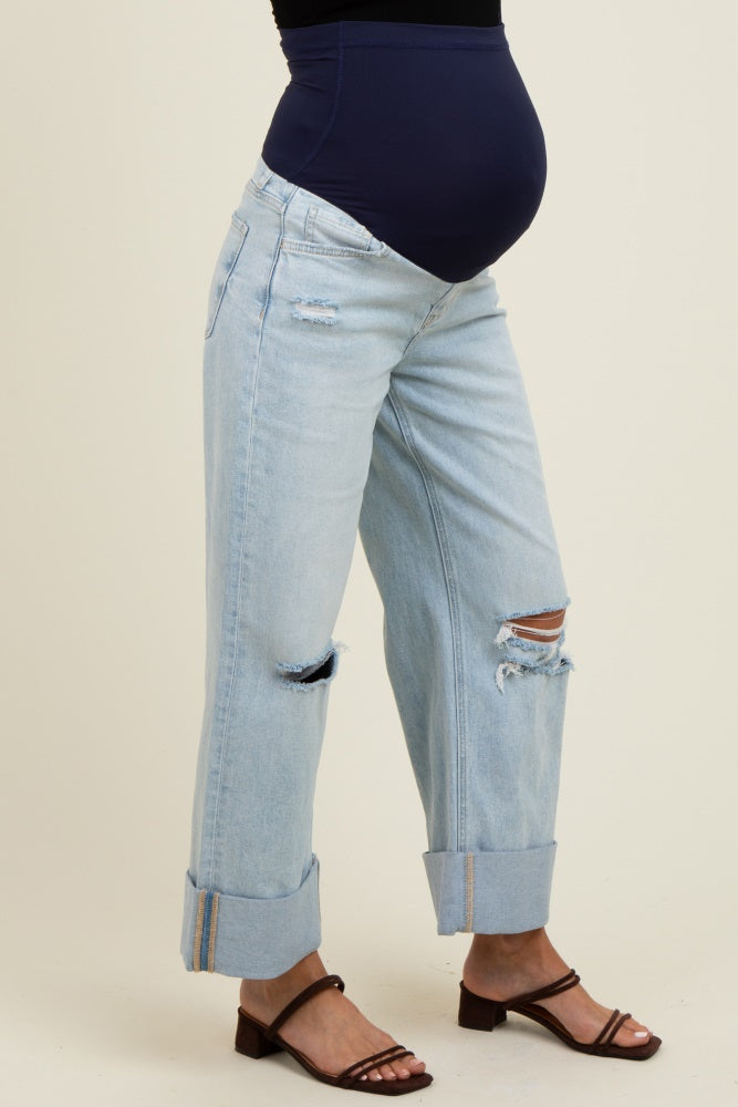 maternity wear light blue distressed boyfriend jeans with cuffed hems and a black maternity belly band, showcasing a baby bump