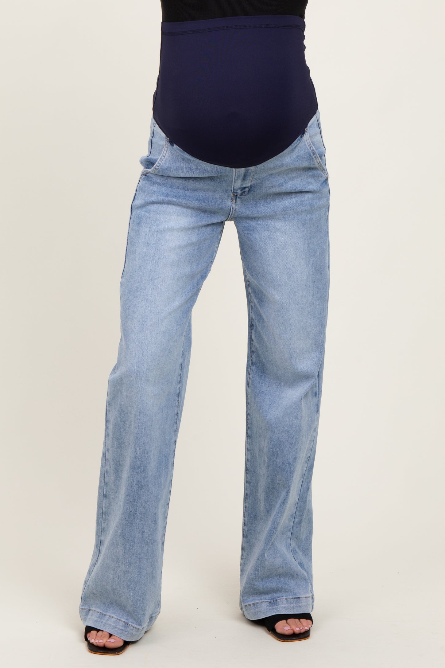 woman wearing light wash maternity jeans with a dark blue over-the-bump waistband