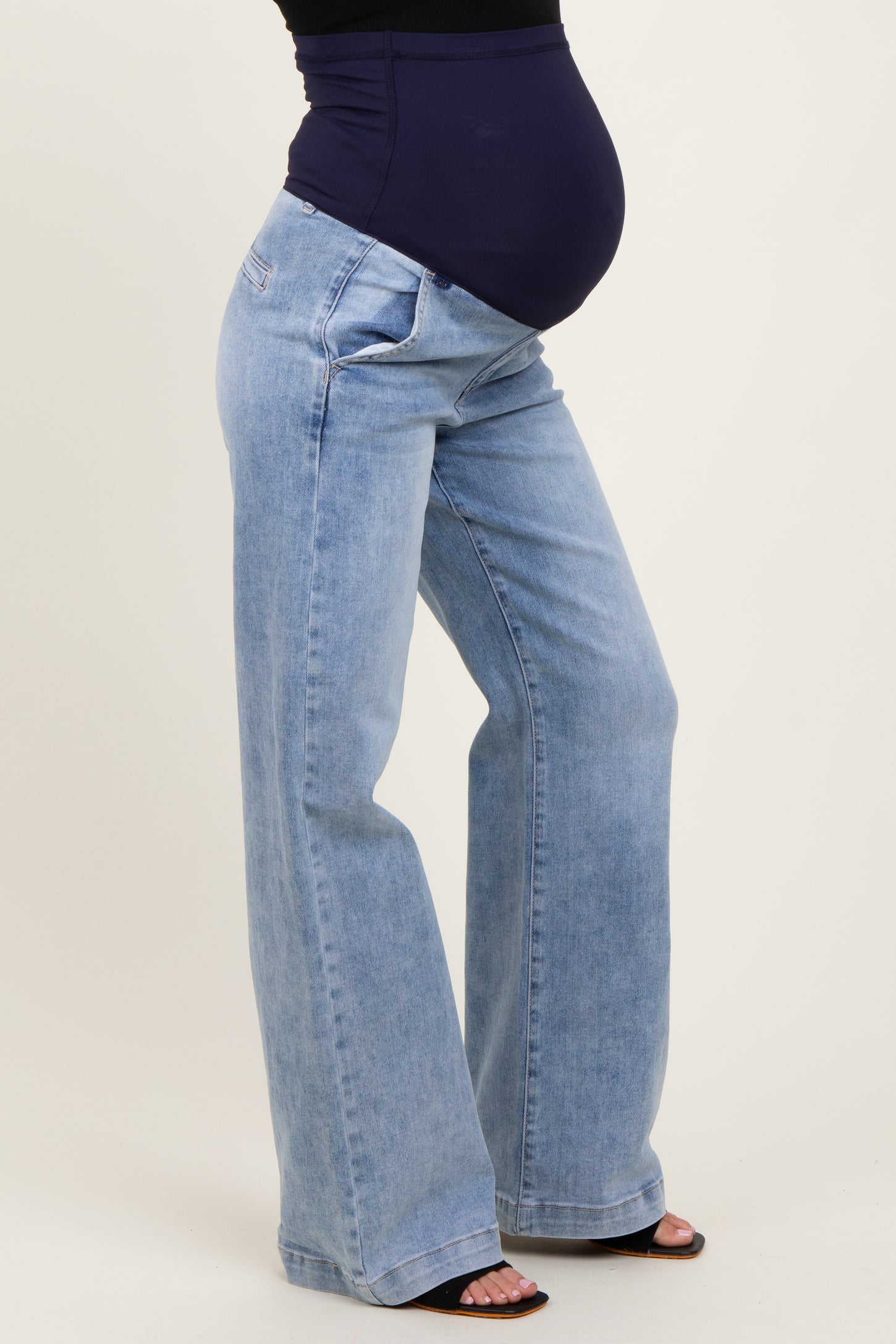 woman wearing a pair of light blue maternity jeans with a fitted waistband and a visible baby bump