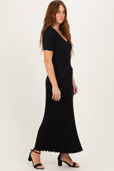 woman wearing a black ribbed maxi dress with a v-neck and short sleeves, standing sideways