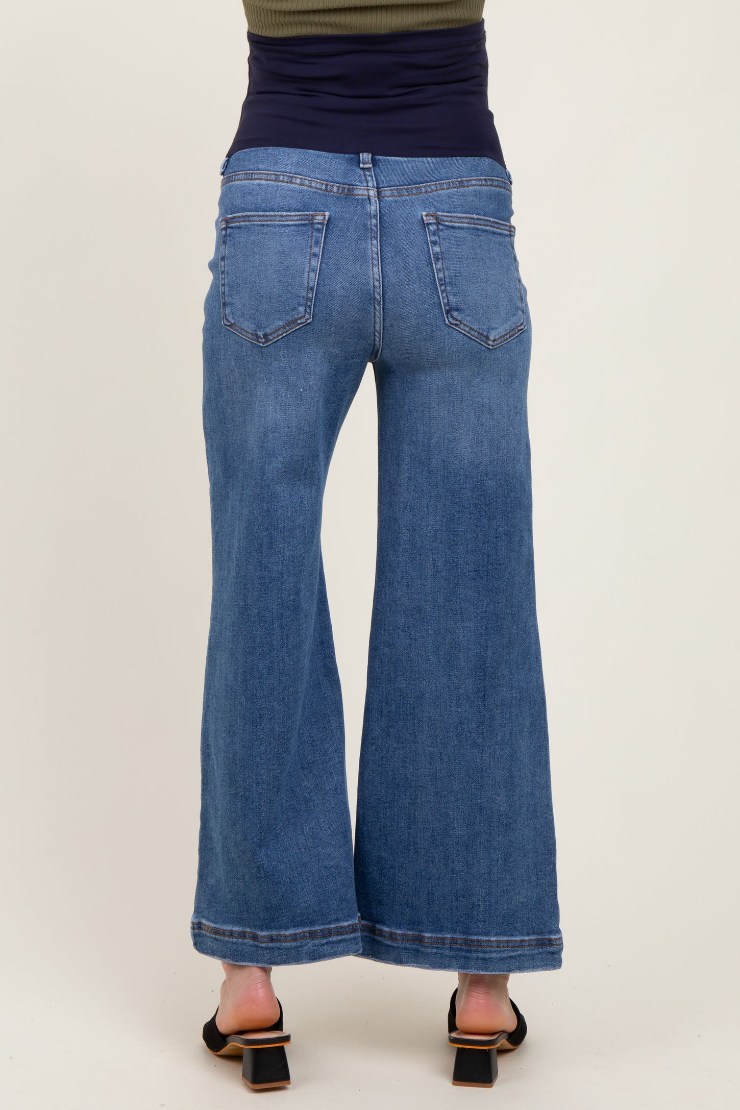 woman wearing maternity wide-leg blue jeans, seen from the back, featuring a high waist and a relaxed fit