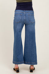 woman wearing maternity wide-leg blue jeans, seen from the back, featuring a high waist and a relaxed fit