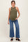 woman wearing a dark green ribbed maternity tank top and light blue wide-leg jeans, holding her baby bump
