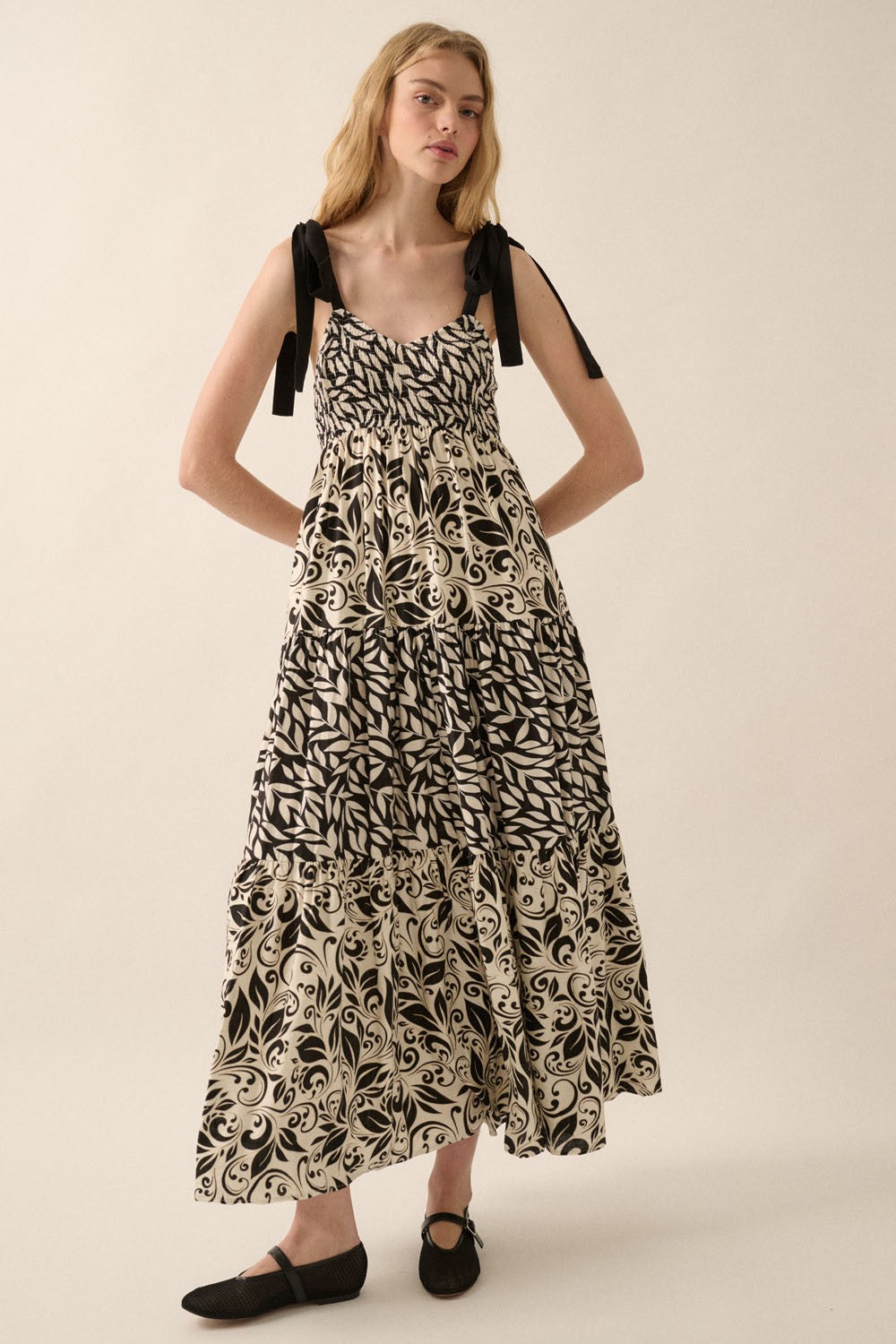 woman wearing a black and white patterned maxi dress with tie straps and a tiered design