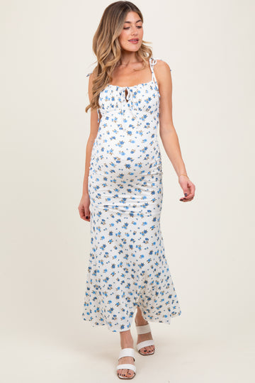 woman wearing a white floral maternity dress with adjustable straps and a fitted silhouette, showing her baby bump