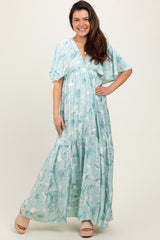 woman wearing a light blue floral maxi dress with flutter sleeves and a tiered skirt