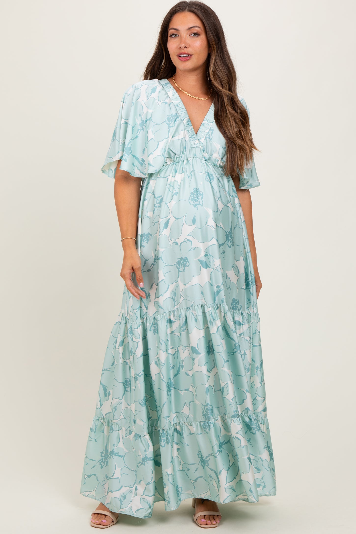 woman wearing a light blue floral maternity maxi dress with flutter sleeves and a baby bump visible