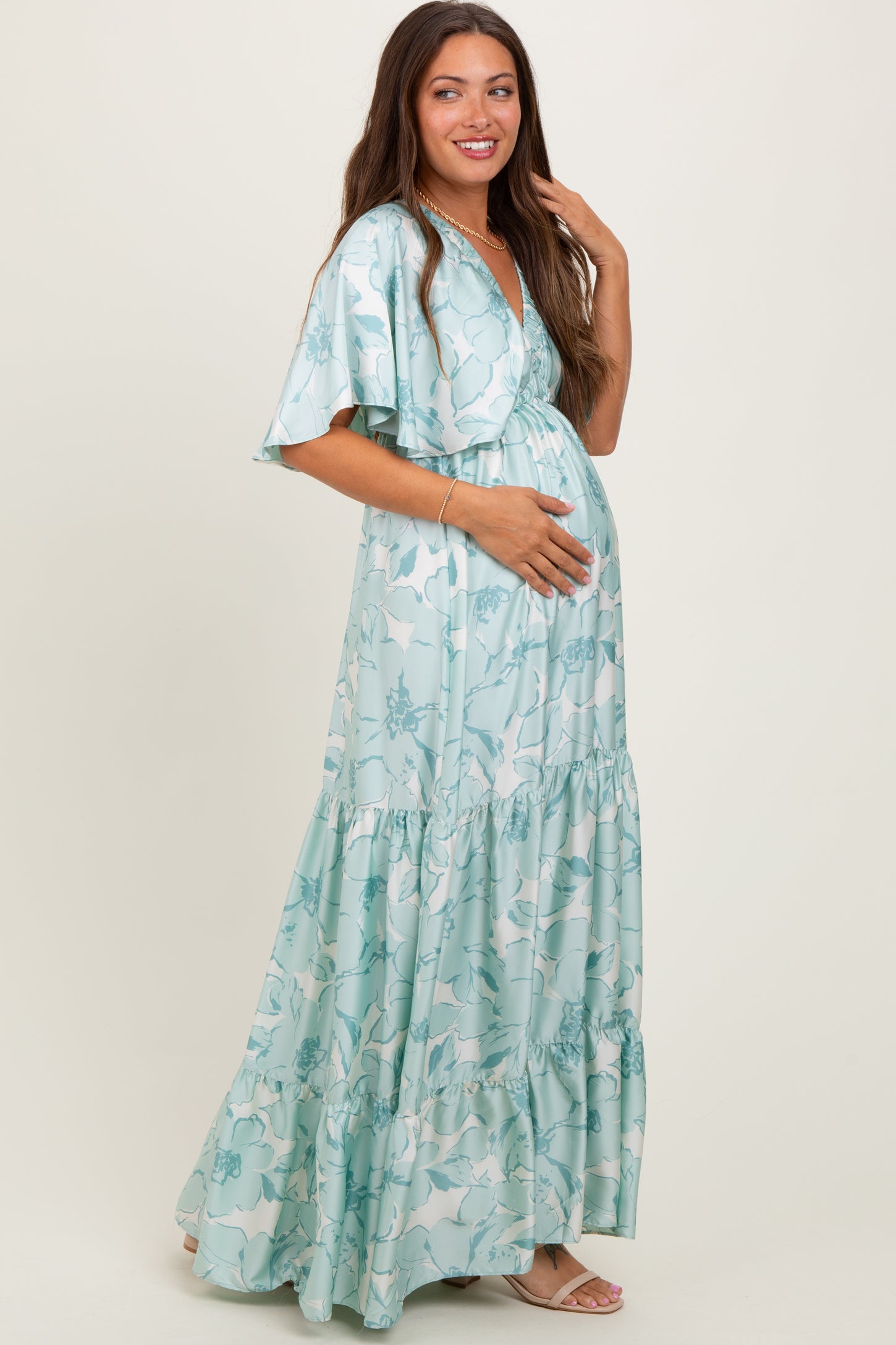 woman wearing a light blue floral maternity maxi dress and holding her baby bump