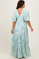 woman wearing a floral mint green maternity maxi dress with a v-back and flutter sleeves