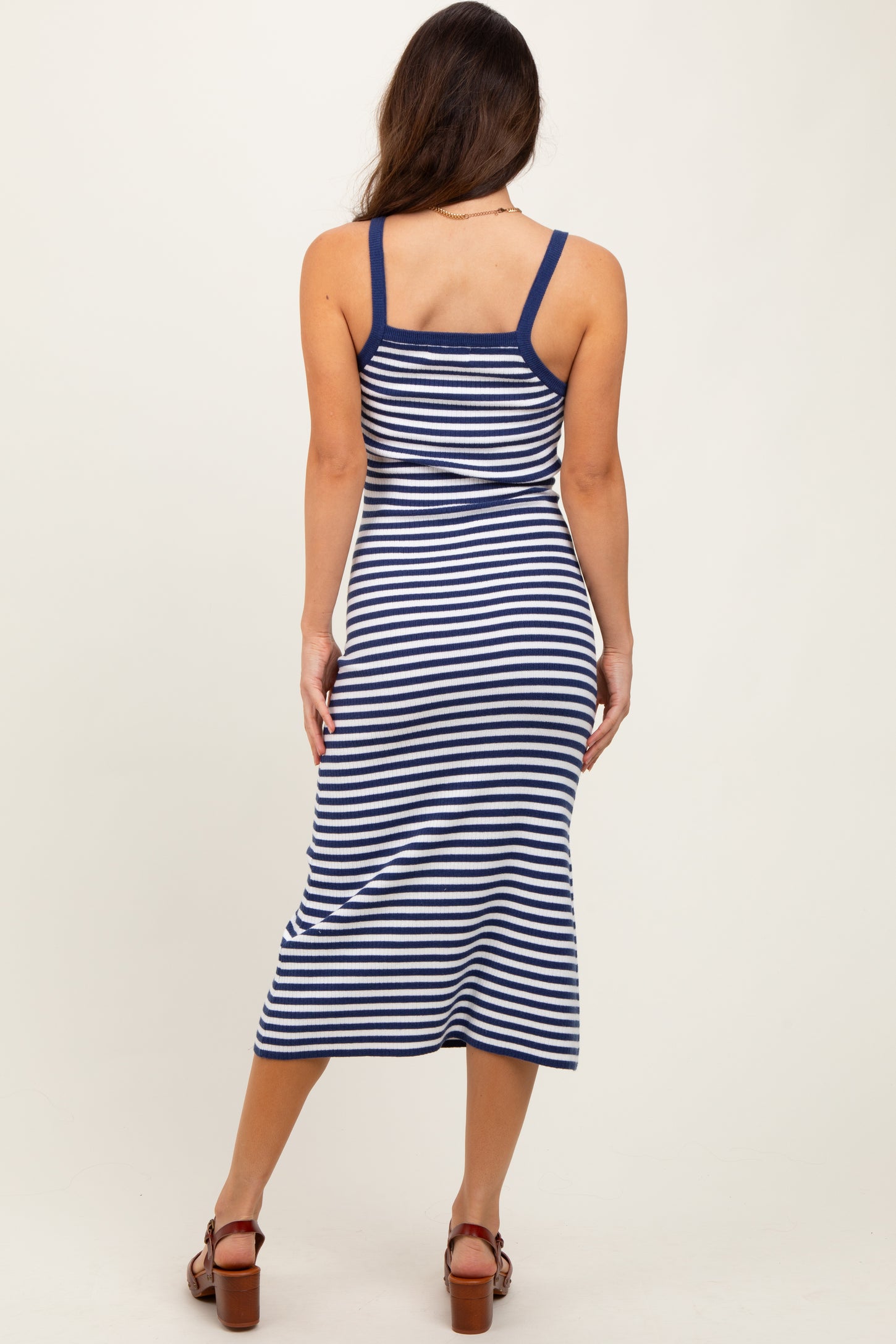 woman wearing a navy and white striped midi dress with a fitted silhouette and spaghetti straps, viewed from the back