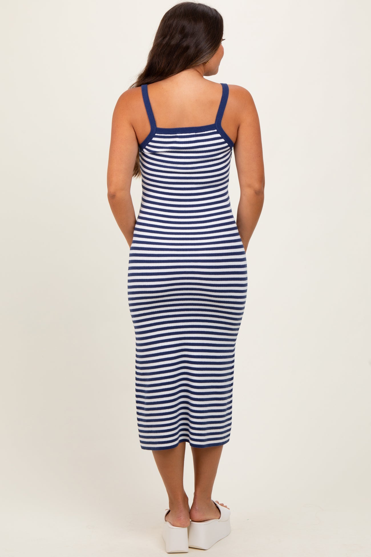 woman wearing a navy and white striped maternity dress with a fitted silhouette and spaghetti straps, showing her back