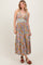 woman wearing a floral maxi dress with a v-neckline and braided details, paired with brown heeled sandals