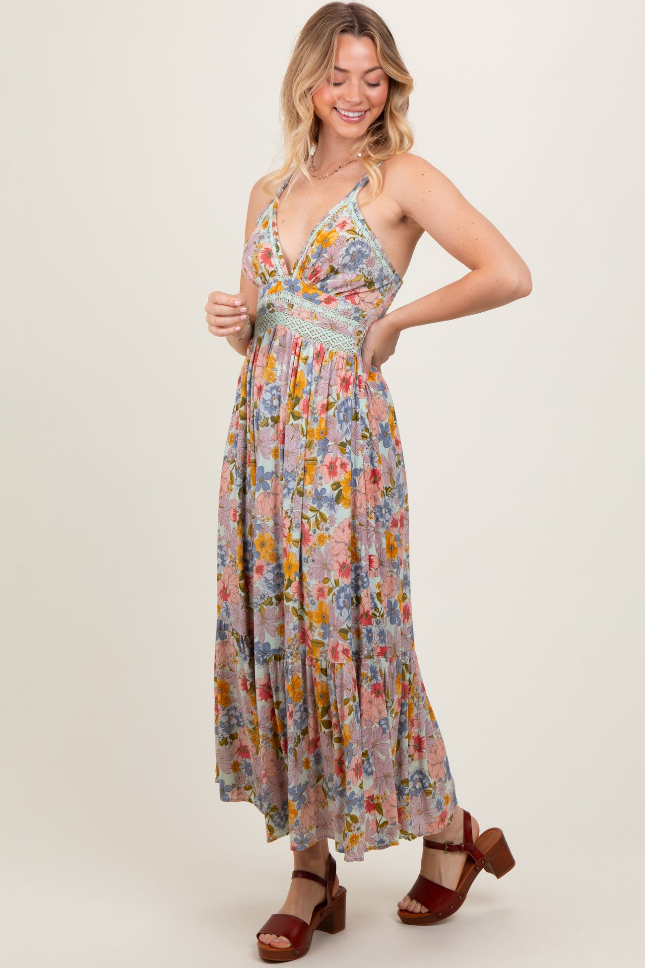 woman wearing a floral maxi dress with a deep neckline and a fitted bodice, styled with brown block heel sandals