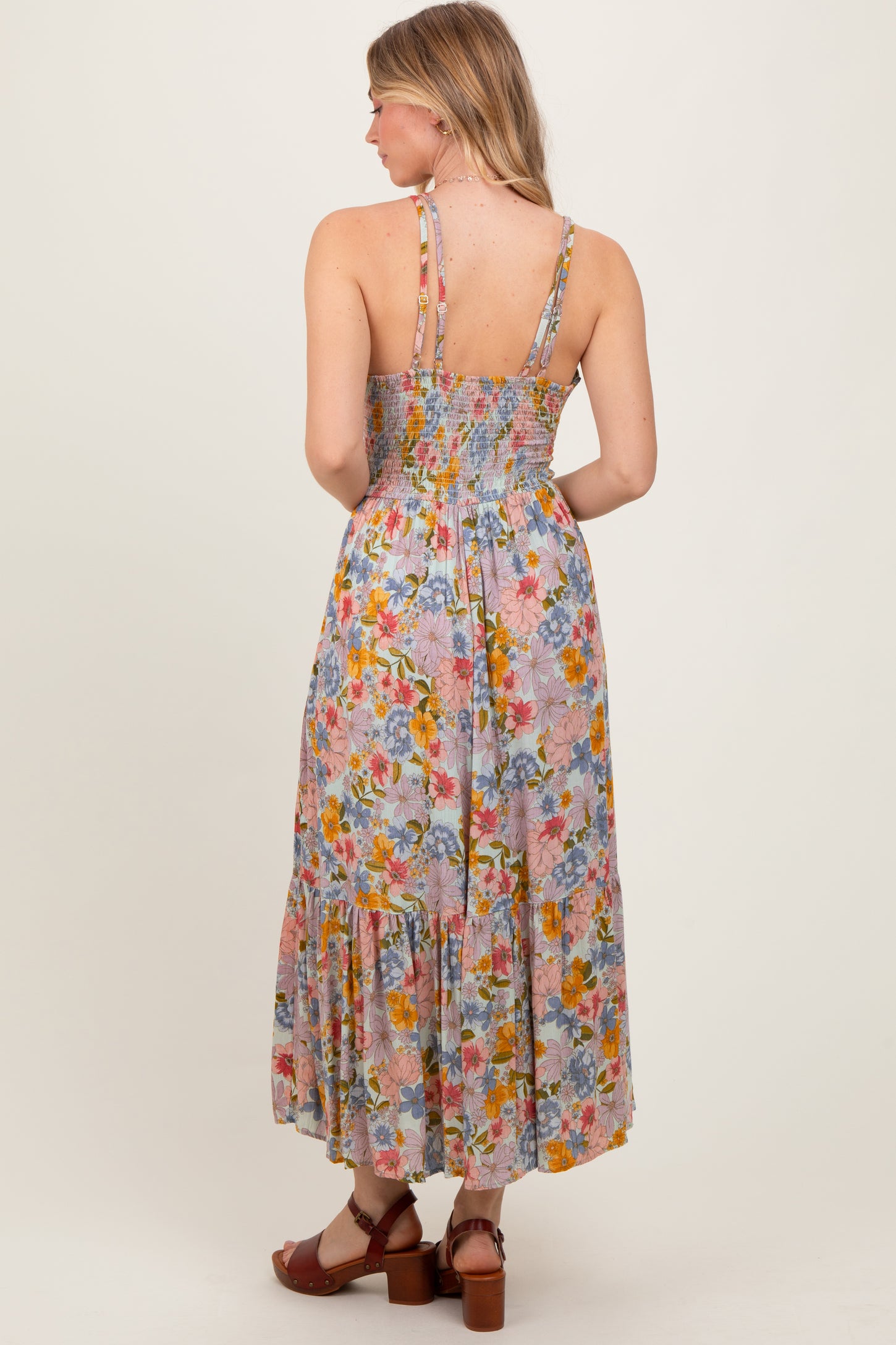 woman wearing a floral maxi dress with a smocked back and tiered hem, showing the back view