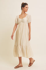 woman wearing a cream puff sleeve midi dress with a smocked bodice and tiered skirt, styled with sandals and layered necklaces