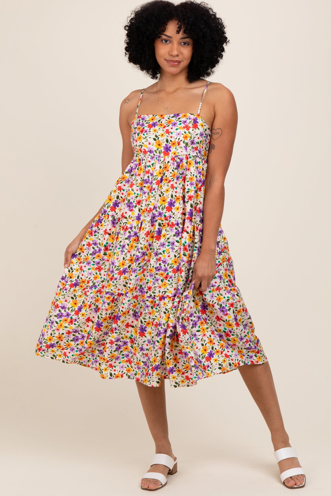 woman wearing a floral print midi dress with spaghetti straps and loose fit, posing against a neutral background