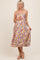 woman wearing a floral maternity dress with adjustable straps and a baby bump, standing and smiling