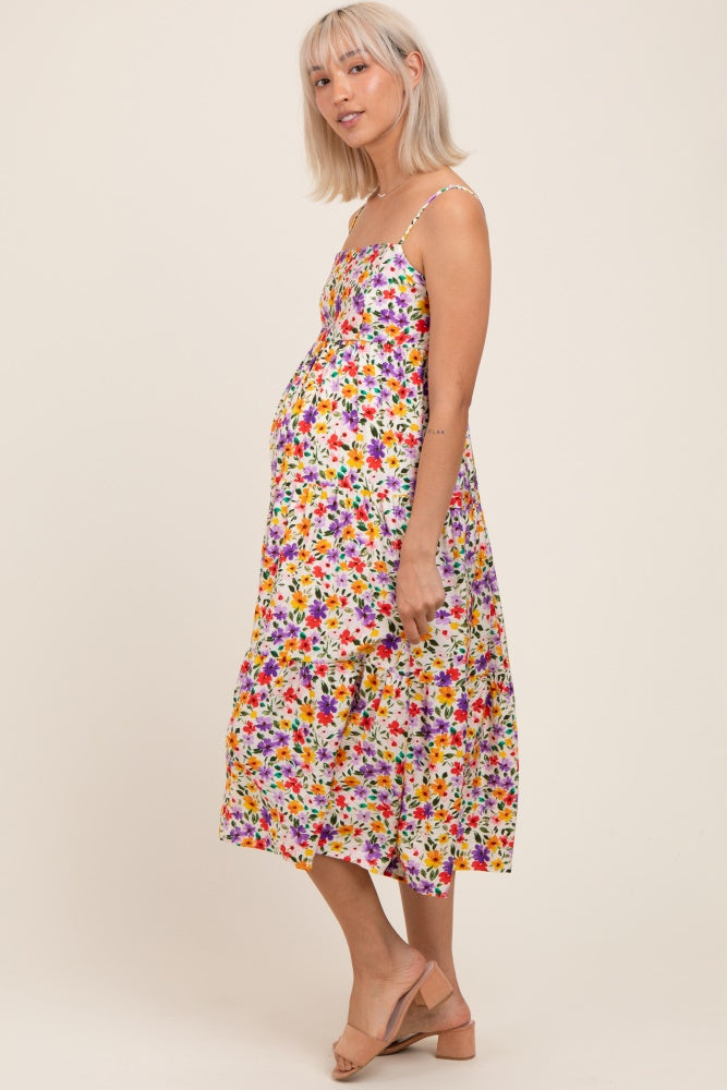 woman wearing a multi-colored floral maternity dress with spaghetti straps and a visible baby bump