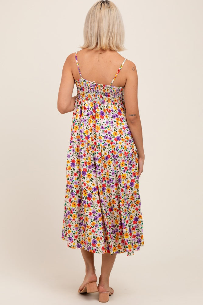 woman wearing a colorful floral maternity maxi dress with adjustable spaghetti straps and a smocked back detail
