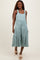 woman wearing a light teal tiered midi dress with adjustable straps and front buttons, standing with a smile