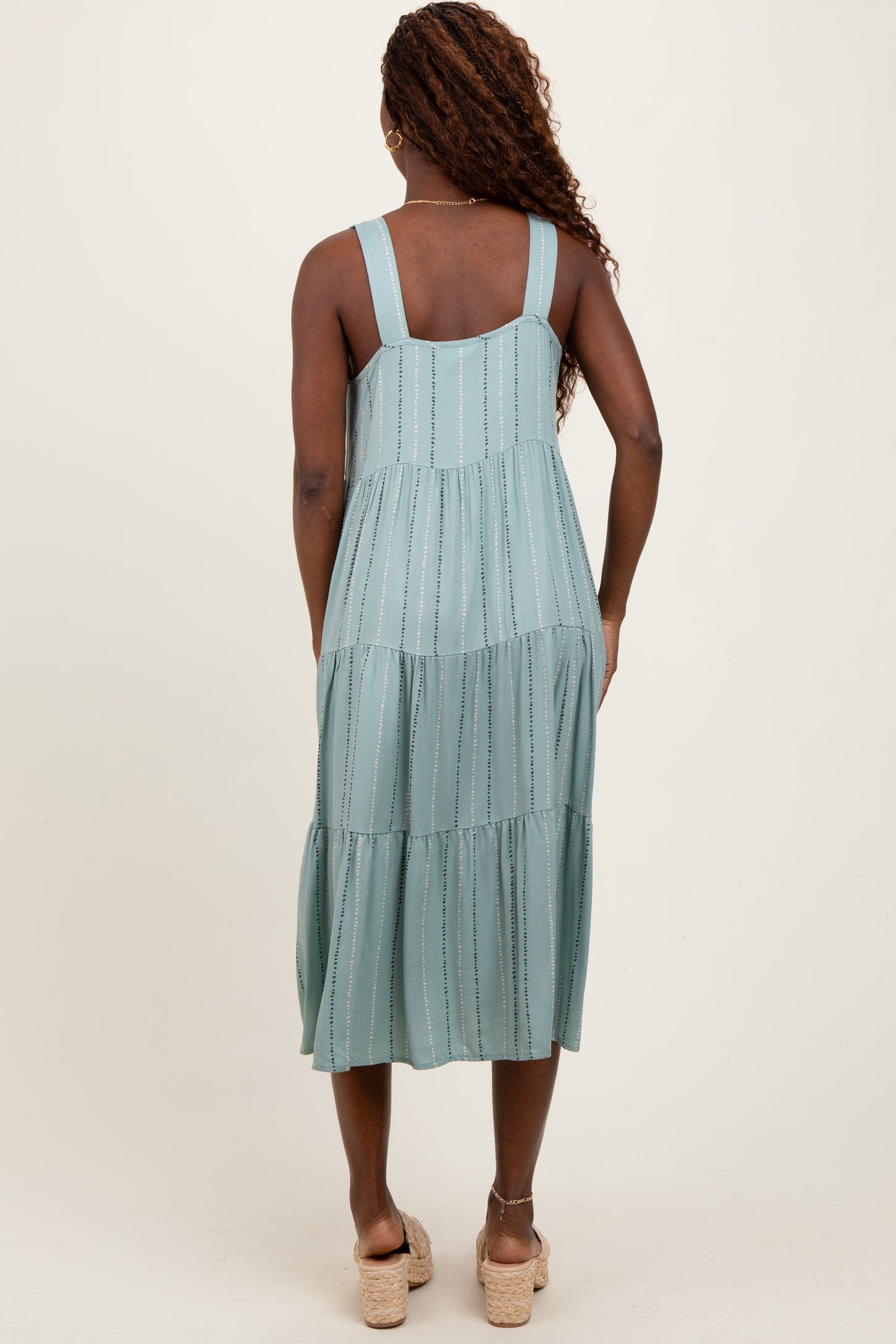 woman wearing a teal tiered midi dress with adjustable straps and a relaxed fit, shown from the back