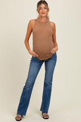 woman wearing a tan ribbed maternity tank top and blue flared jeans, showcasing her baby bump