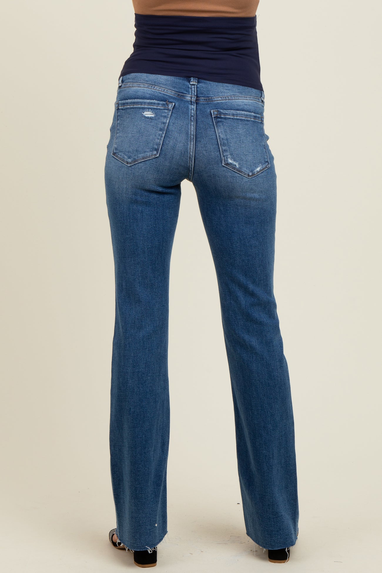 woman wearing a pair of blue bootcut maternity jeans, showing the back view with subtle distressing details